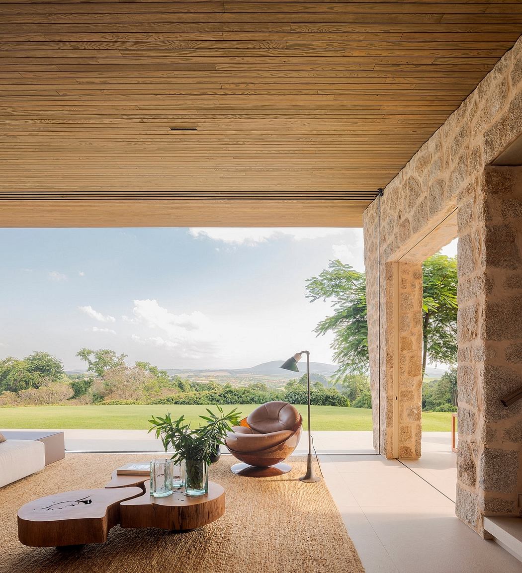 Contemporary patio with wooden ceilings, stone walls, and scenic view.
