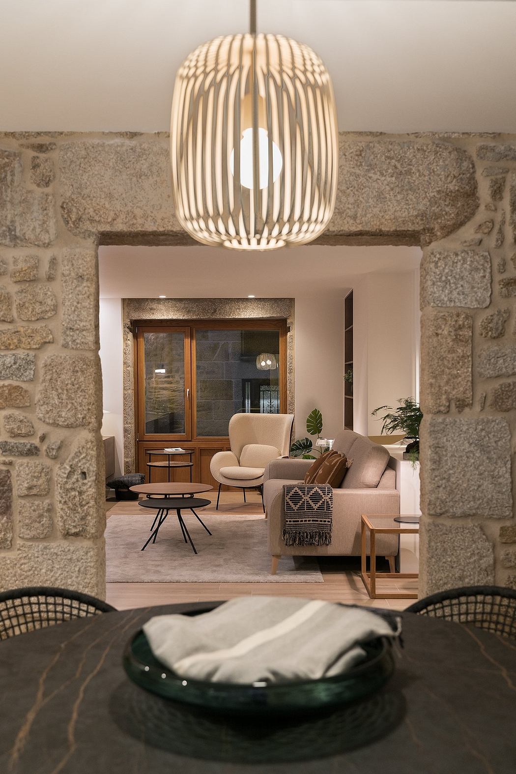 Elegant interior with modern pendant light, stone archway, and cozy living room
