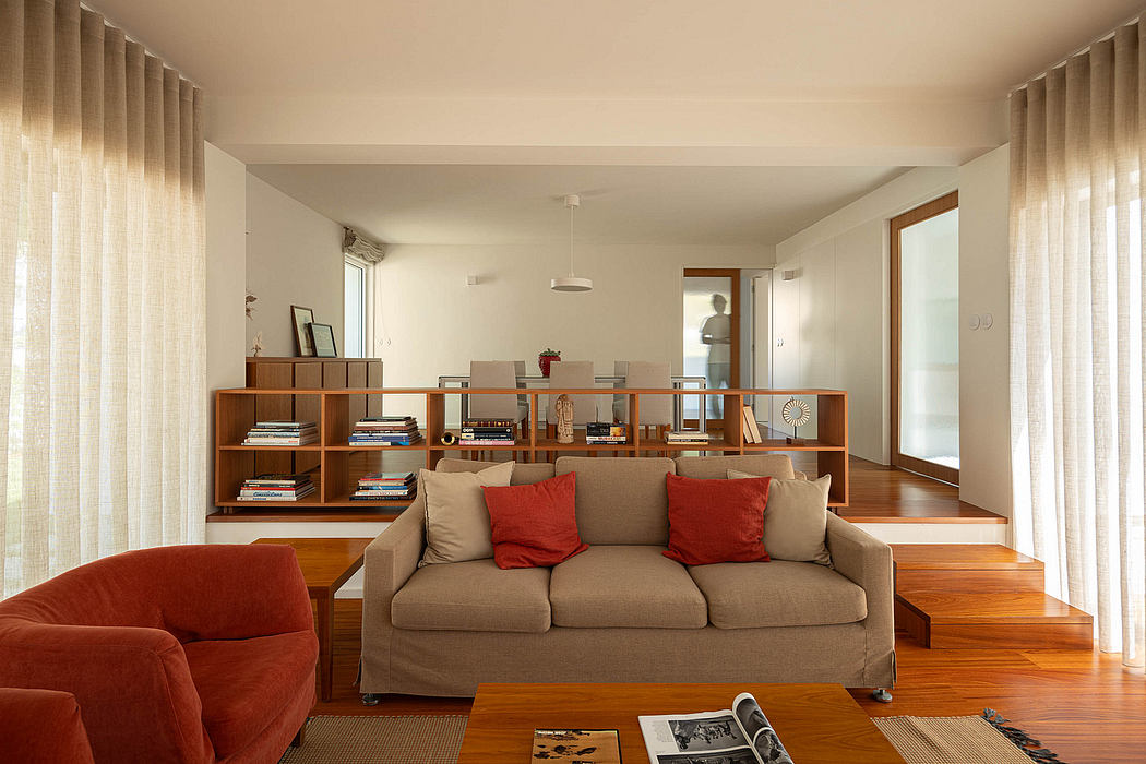 Modern living room with beige sofa, wooden floors and furniture, and sheer curtains.