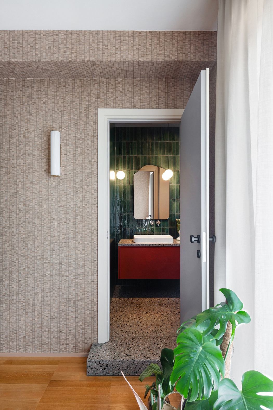 Modern bathroom viewed through an open door from a room with textured wallpaper and a house