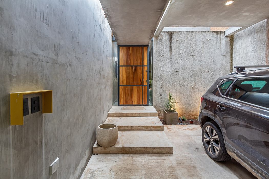 Minimalist concrete entryway with a car parked beside steps leading to a wooden door