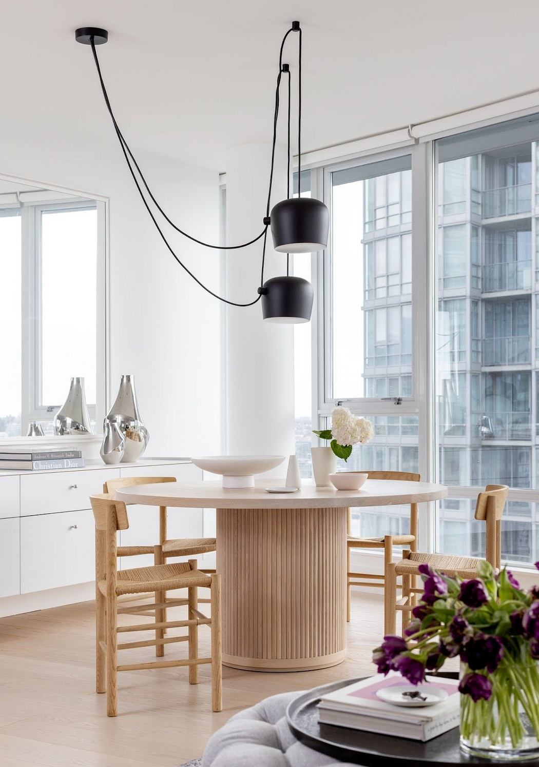 Minimalist dining space with sculptural light fixture and city view.
