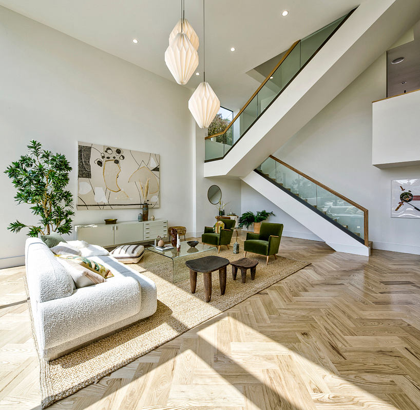 Bright living space with soaring ceilings and floating staircase.