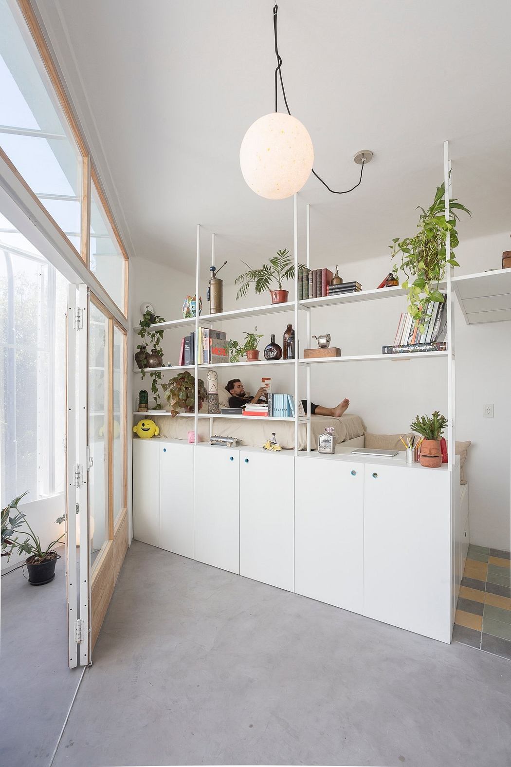 Bright room with white storage shelves, plants, and a pendant light.