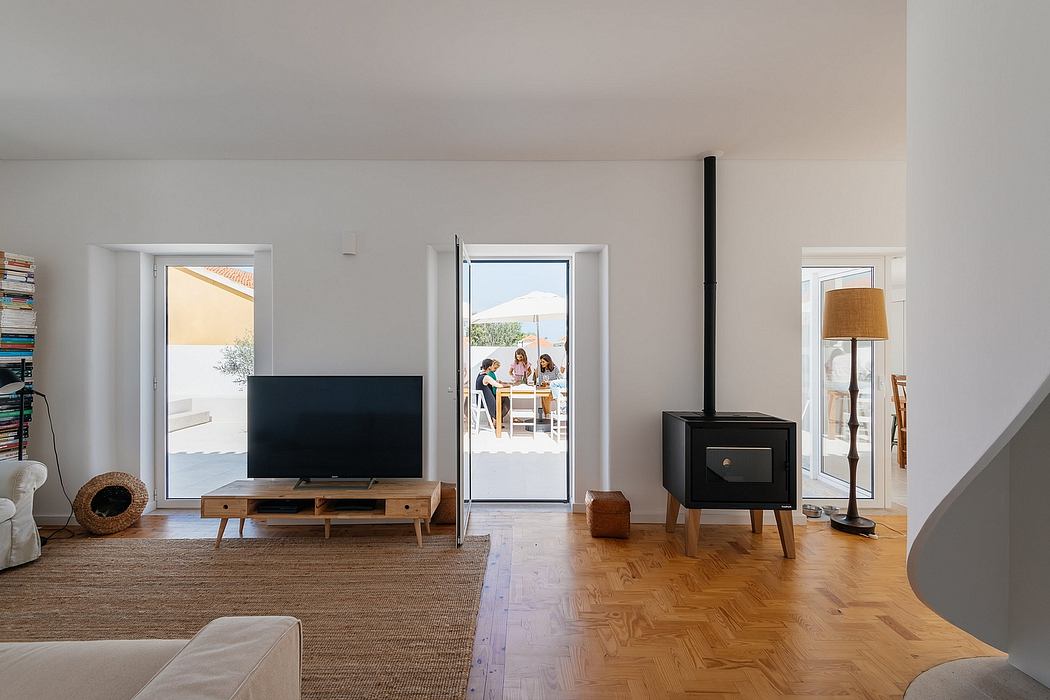 Bright minimalist living room with wood floors and white walls, leading to an outdoor patio