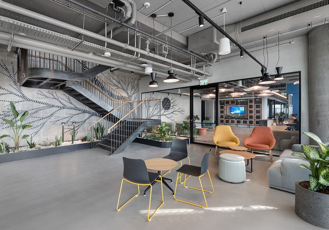 Modern office interior with colorful chairs, plants, and an industrial staircase.