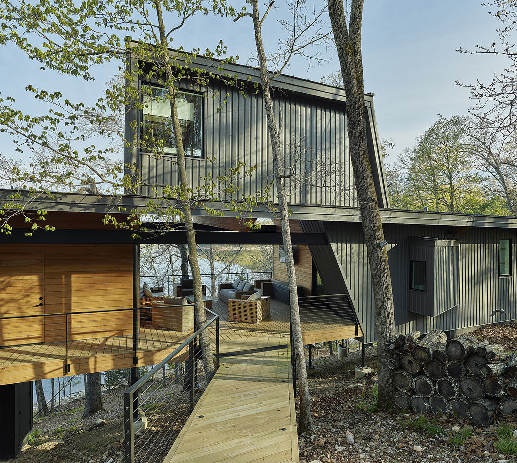 Contemporary forest house with large windows and a wooden walkway.