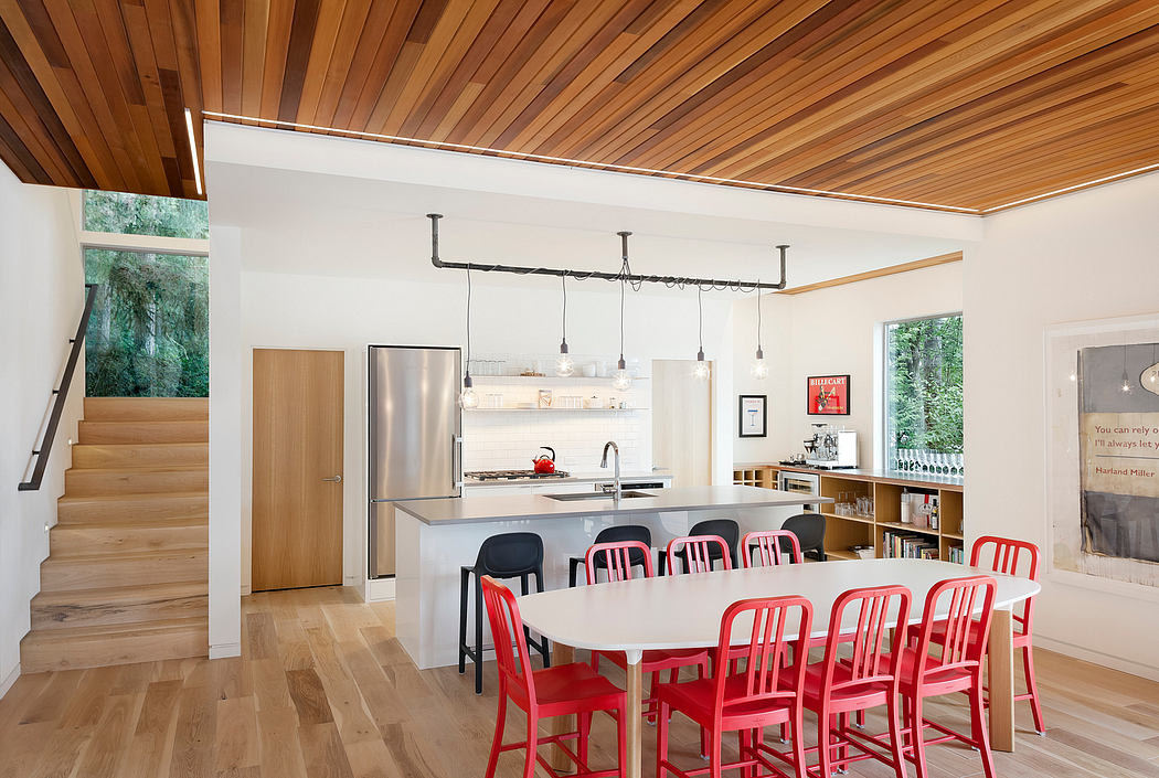 Modern kitchen with wooden ceiling, red chairs, and a dining area.