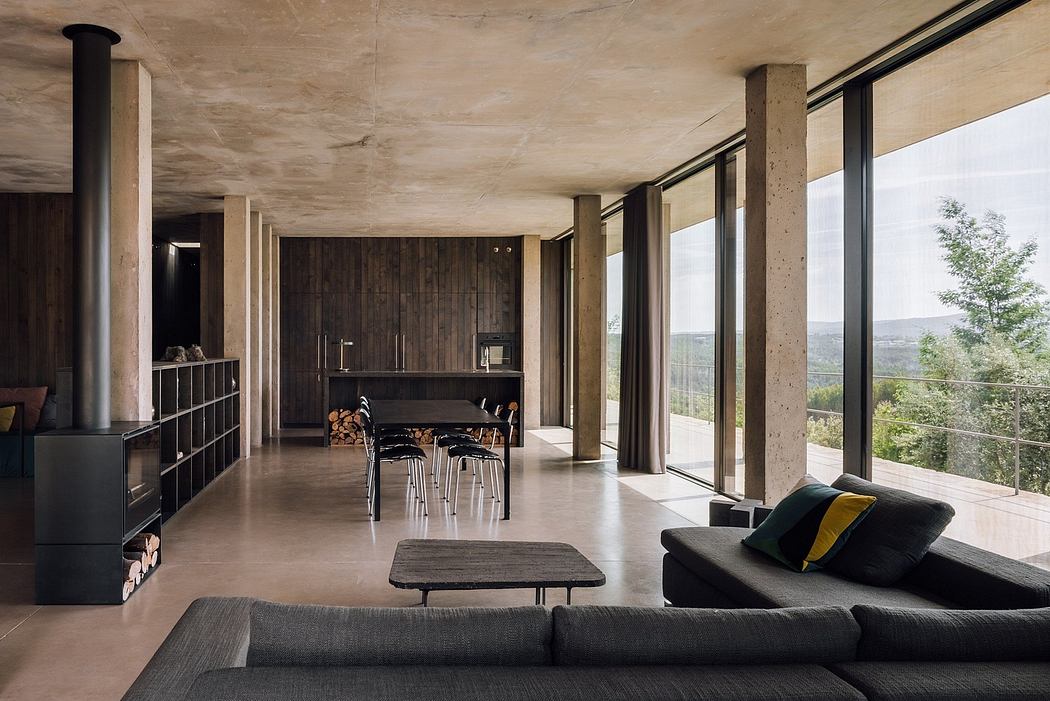 Contemporary open-plan living space with concrete walls, floor-to-ceiling windows,