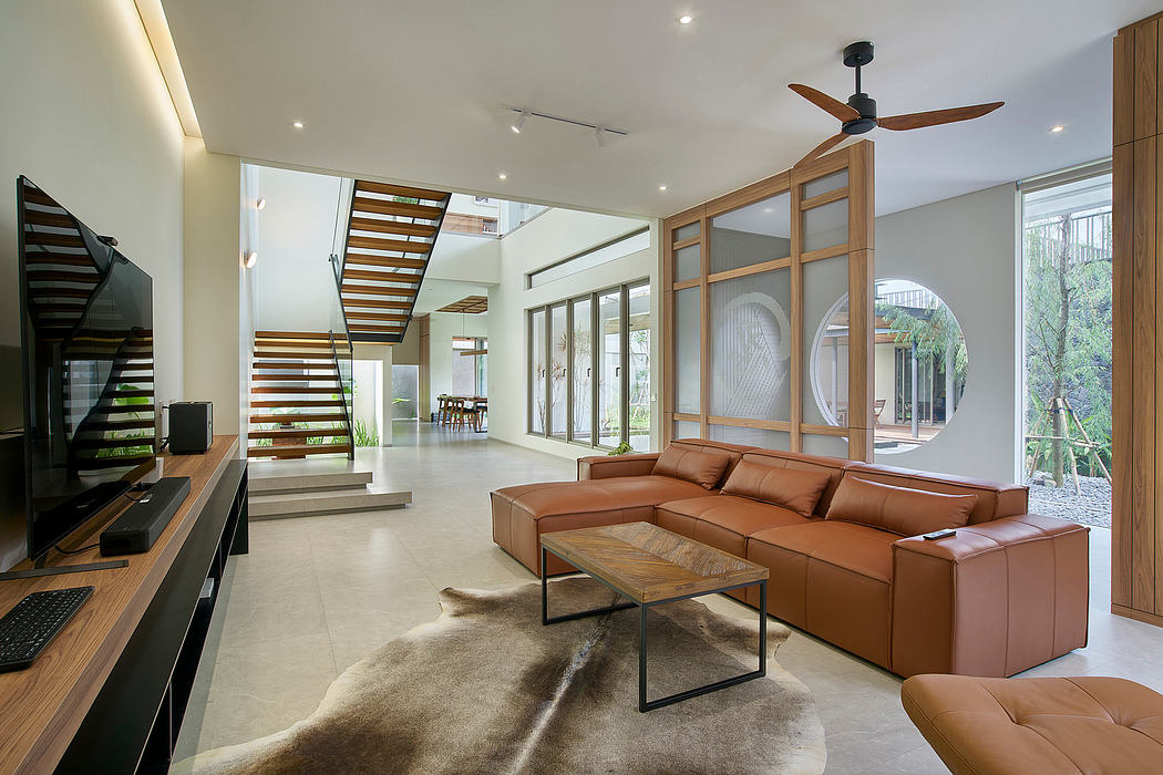 Modern living room with leather sofa, large windows, and open staircase.