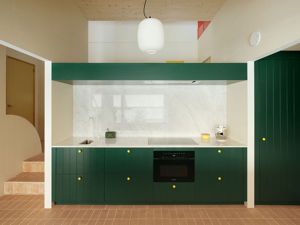 Modern kitchen with green cabinets, terracotta tiles, and a white ceiling lamp