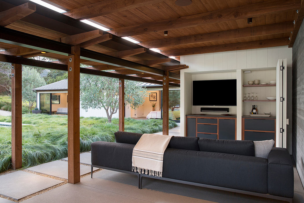Modern living room with wooden ceiling, large sofa, and view of outdoor garden.