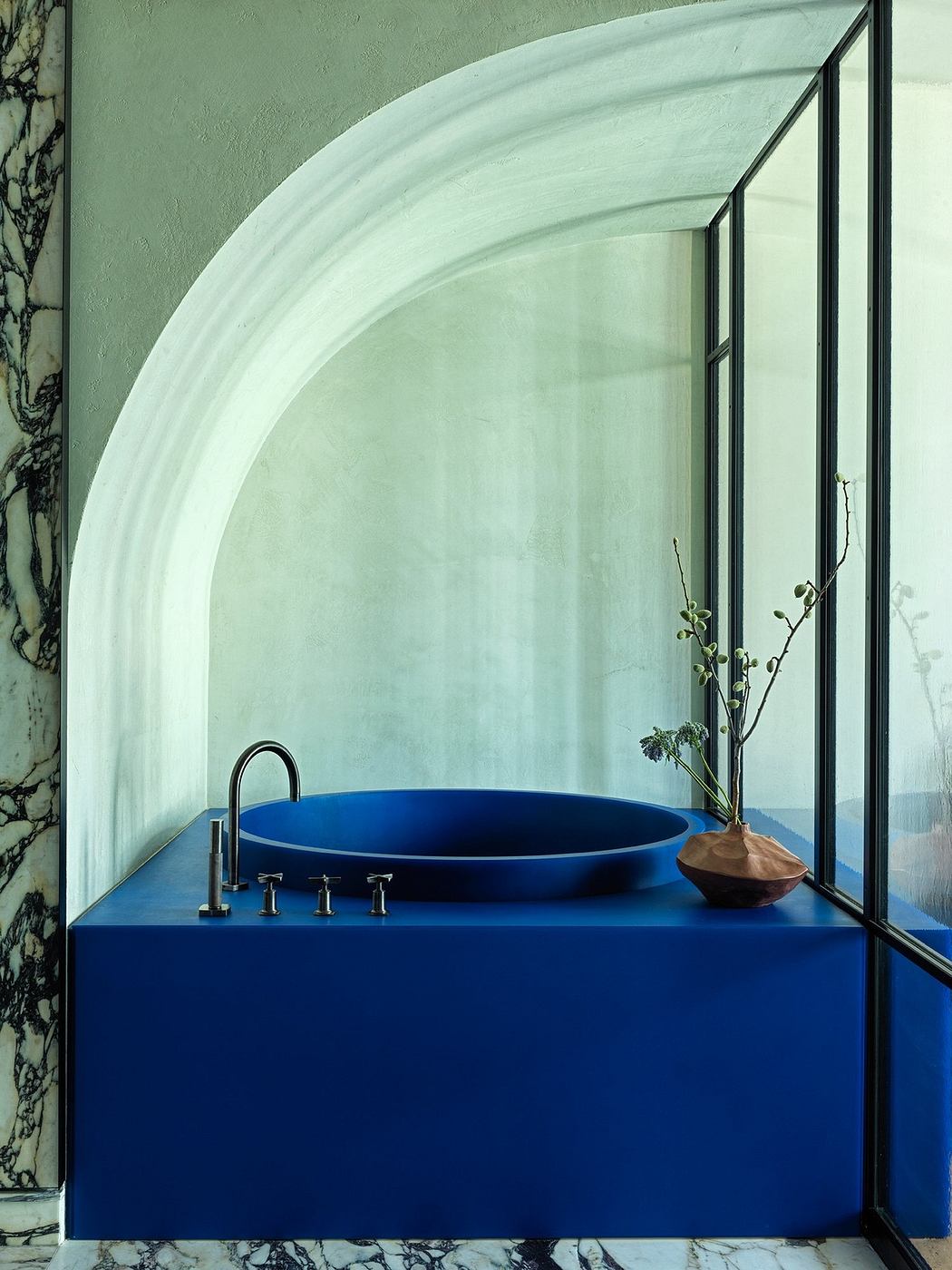 Modern bathroom with blue sink and arched niche.