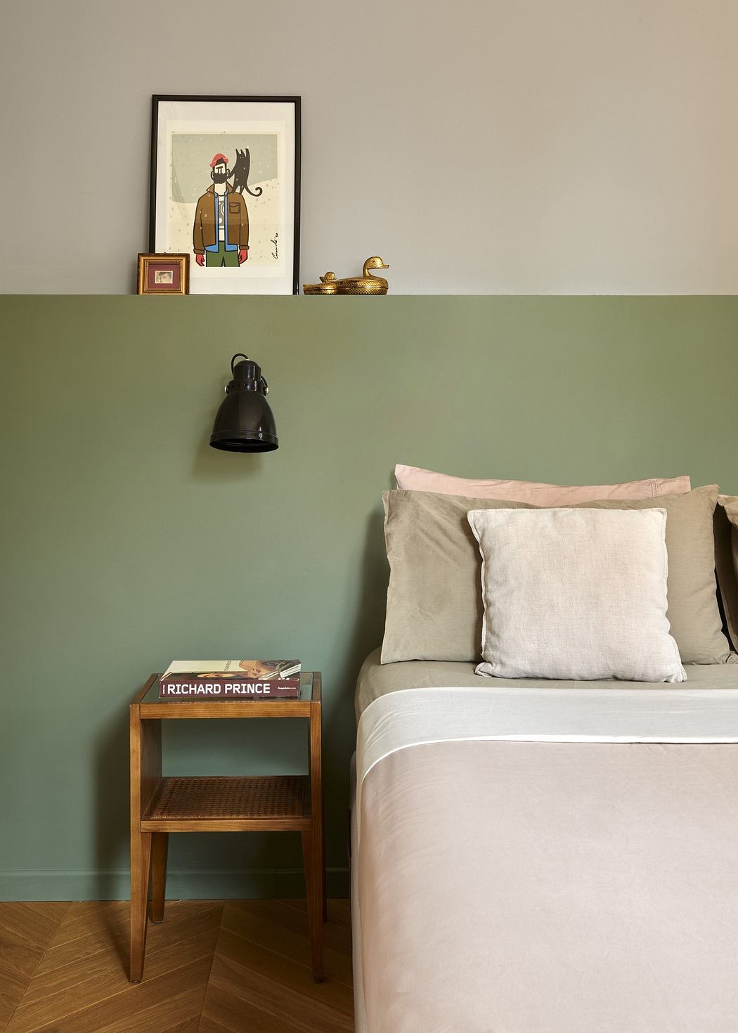 A cozy bedroom corner with a two-tone wall, art frame, side table with