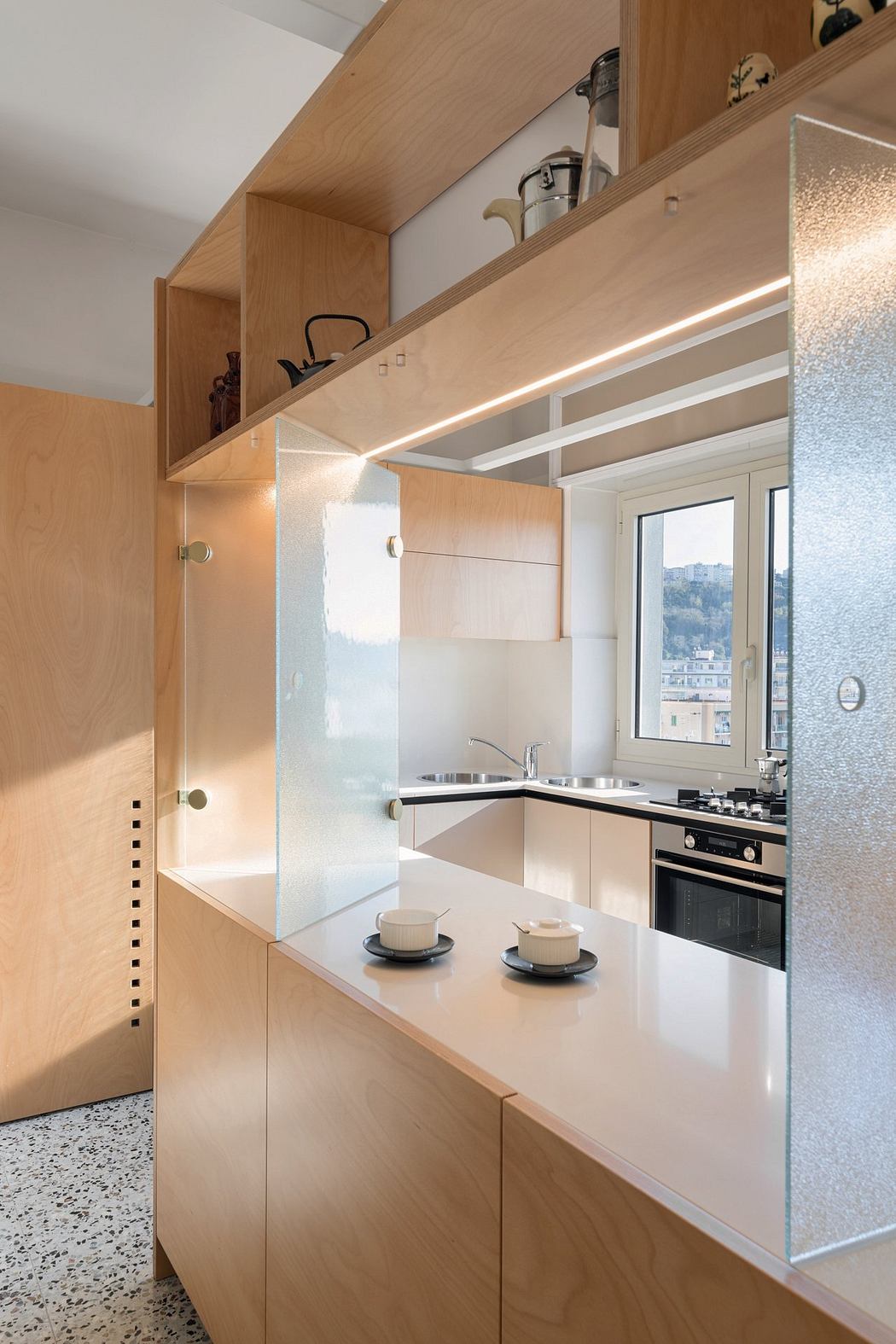 Modern kitchen with wooden cabinets, frosted glass, and built-in lighting.