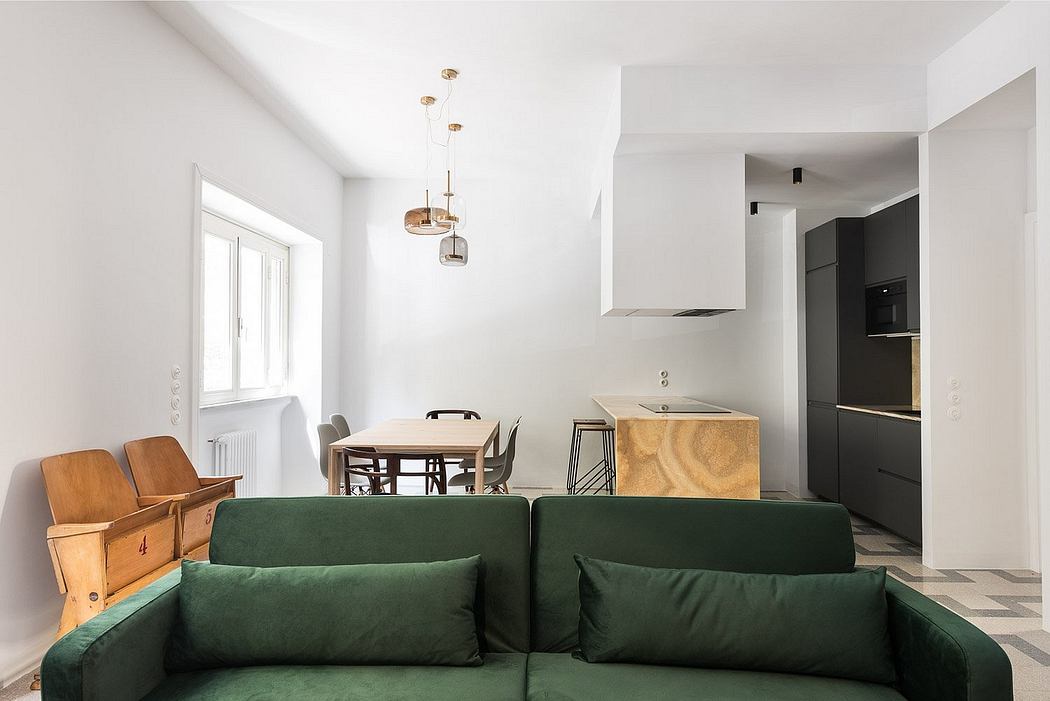 Minimalist living room with green sofa and open kitchen.