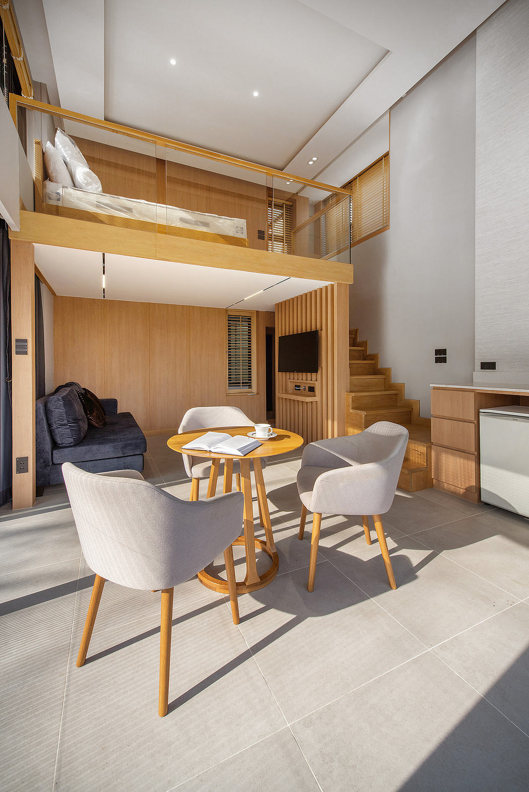 Modern minimalist interior with wooden furniture and staircase leading to a loft.