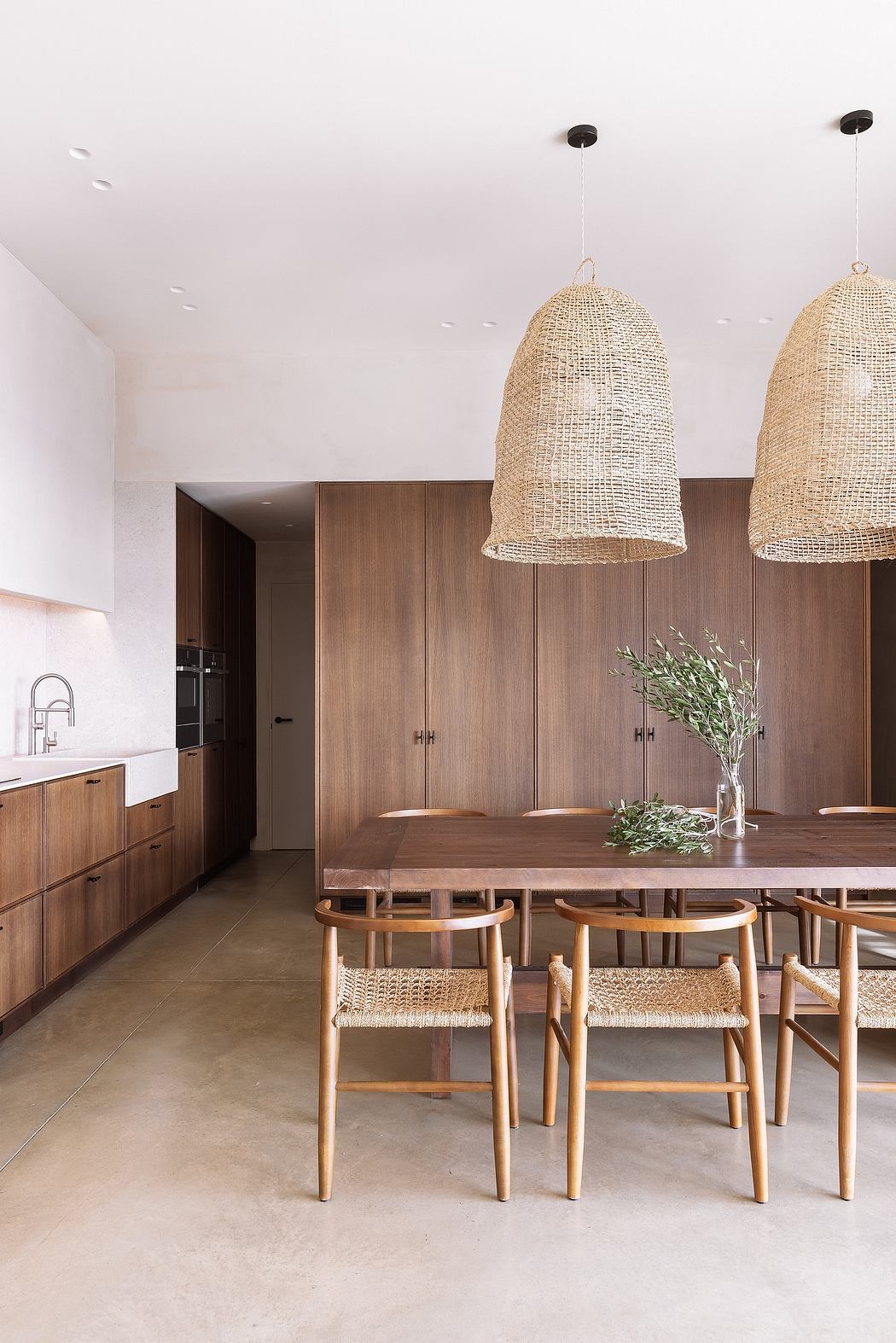 Modern kitchen with wooden cabinets, a dining table, chairs, and pendant lights.
