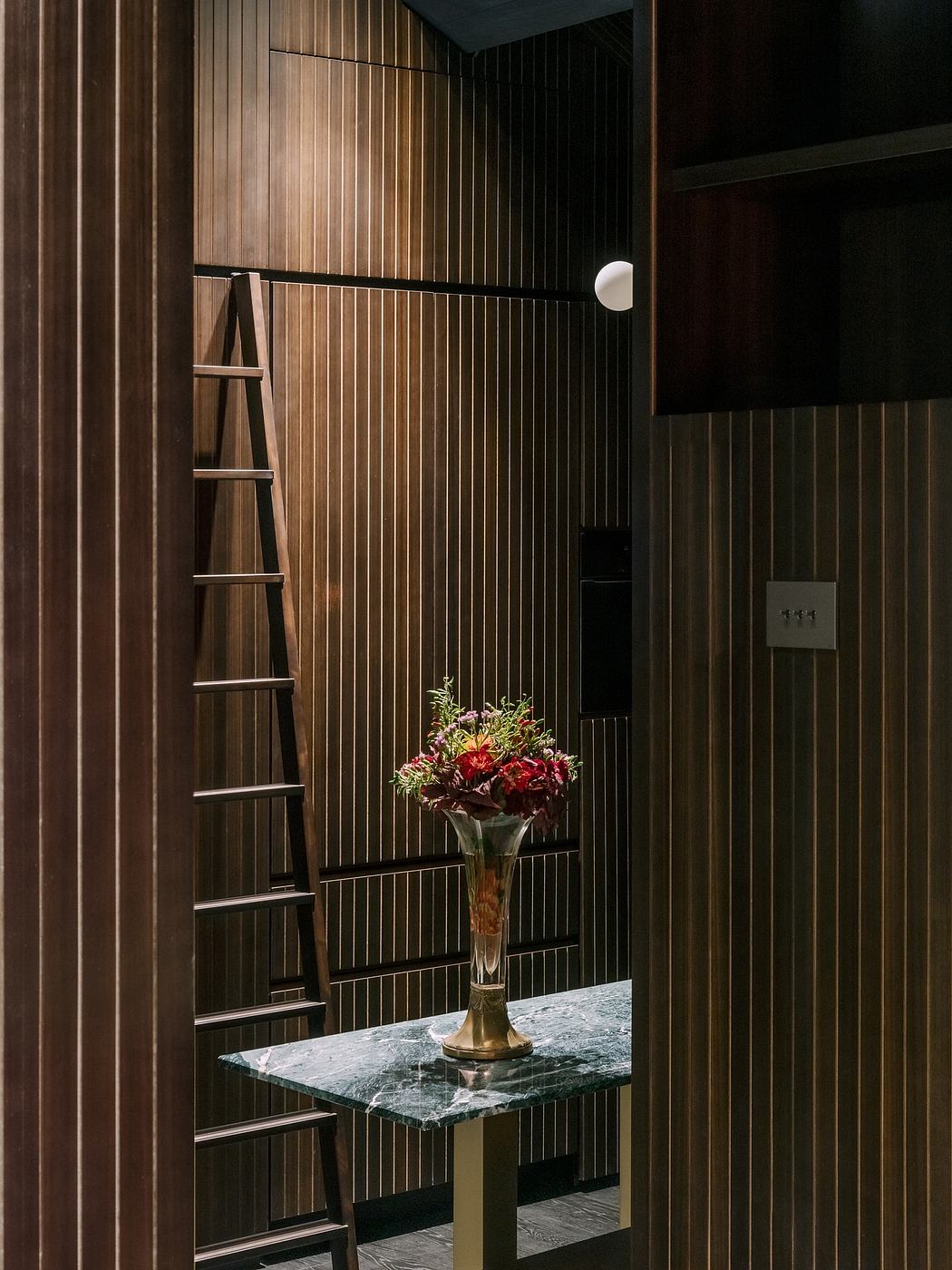 Contemporary hallway with vertical wood paneling and decorative flowers on a table.