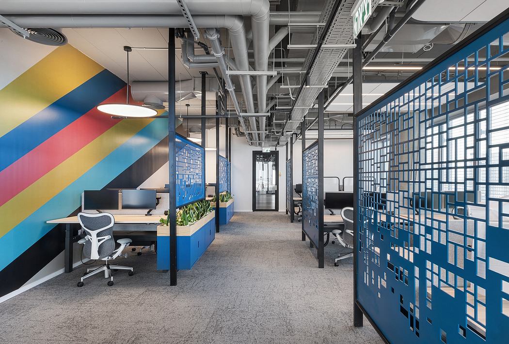 Colorful contemporary office with geometric wall design and exposed ceiling pipes.