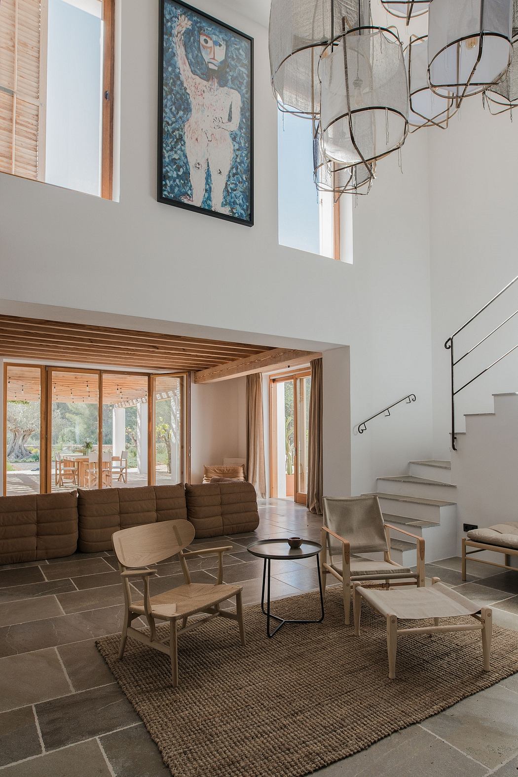 Bright, airy living space with high ceilings, staircase, and striking light fixtures.