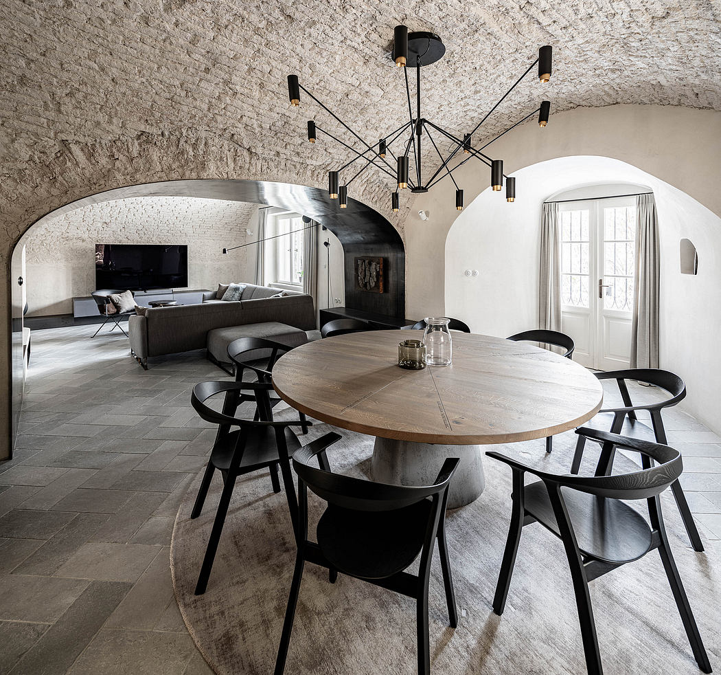 Contemporary room with a vaulted stone ceiling, circular wood table, and artistic