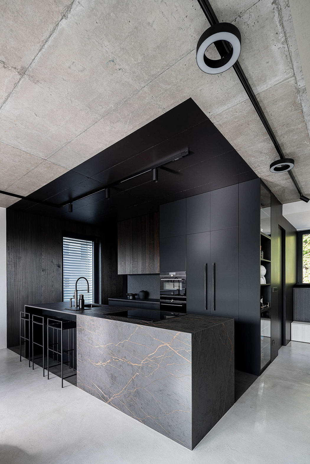 Modern kitchen with black cabinetry and exposed concrete ceiling.