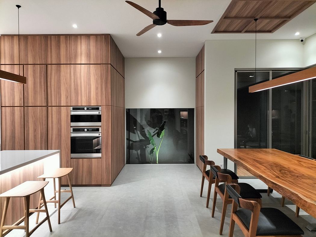 Modern kitchen with wooden cabinets, built-in appliances, and a long dining table.