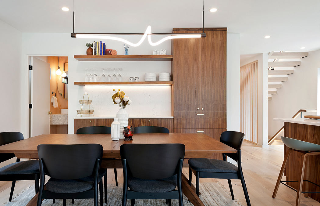 Contemporary dining room with wooden table, black chairs, and minimalist decor.