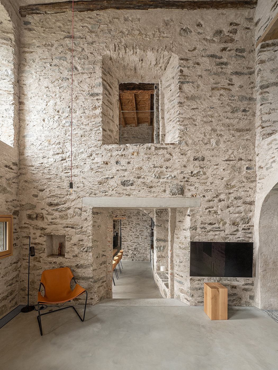 Interior of a stone-walled room with modern furnishings and a fireplace.