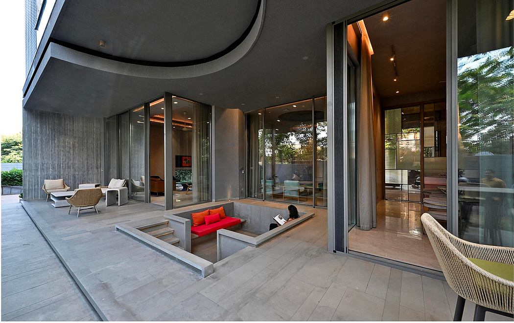 Modern patio with concrete seating area, large glass windows, and sliding doors.