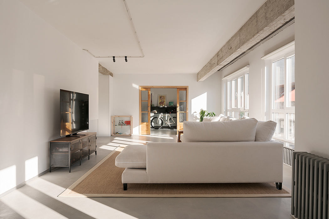 Modern living room with white sofa, TV, and large windows.