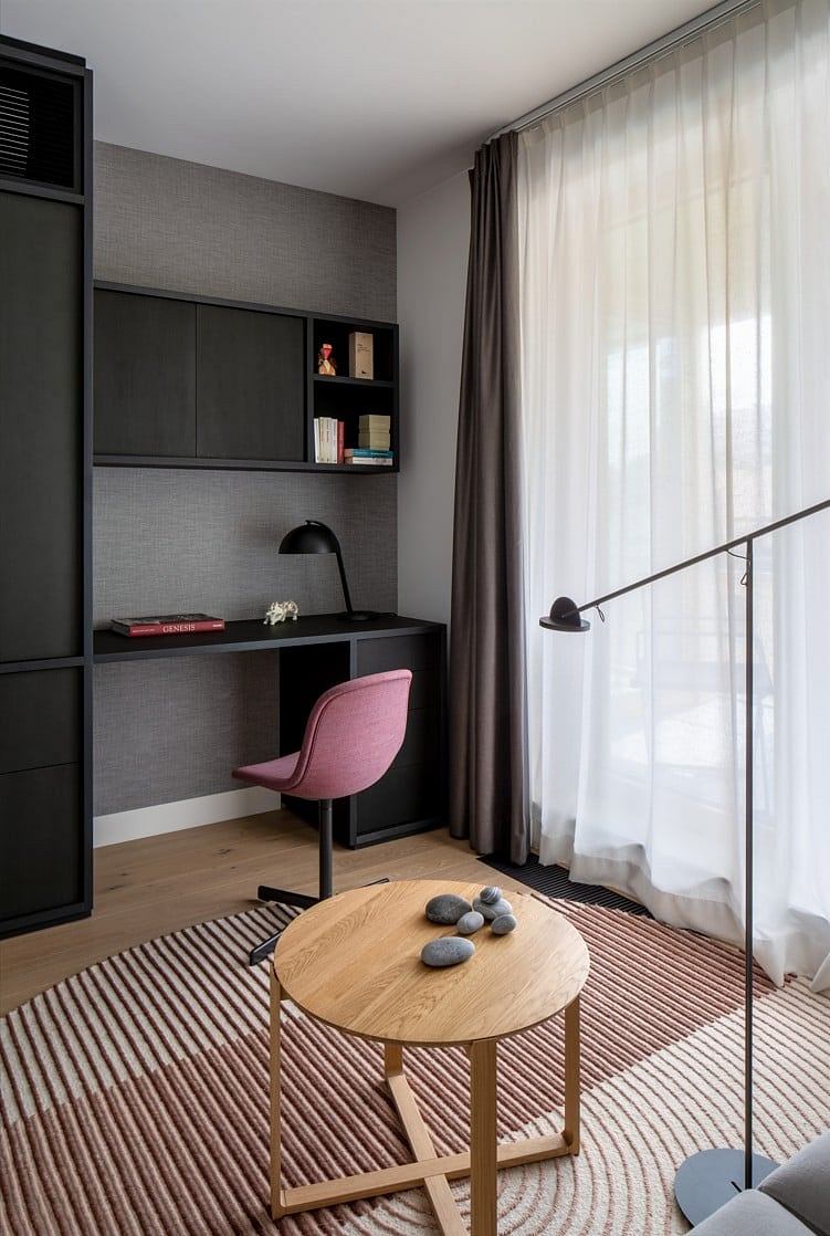 Contemporary home office with pink chair and built-in shelves.
