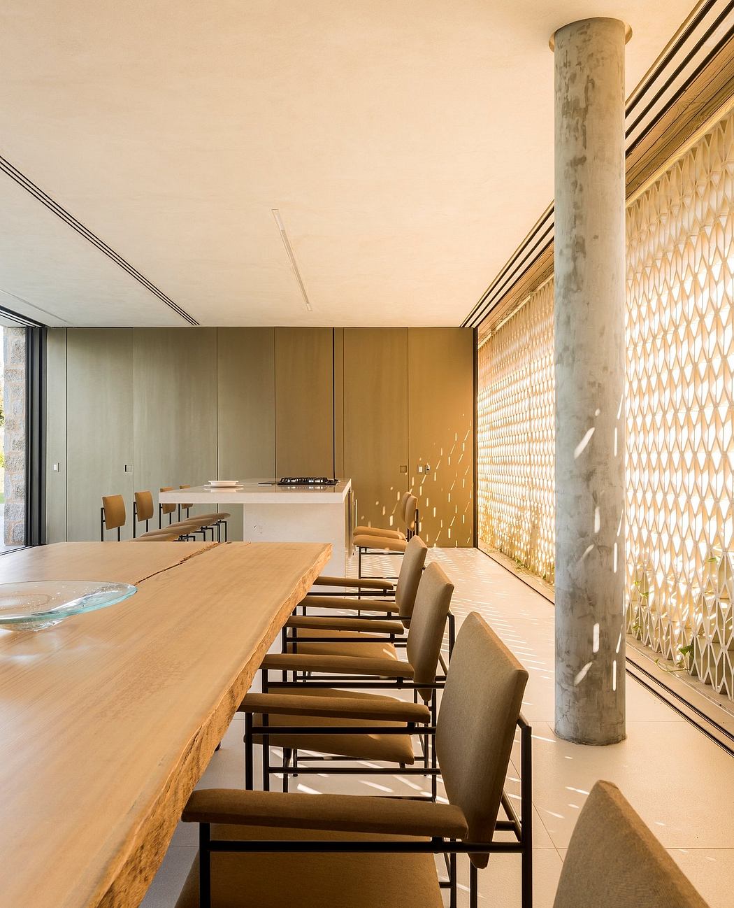 Minimalist dining space with a long table, concrete column, and geometric wall panels