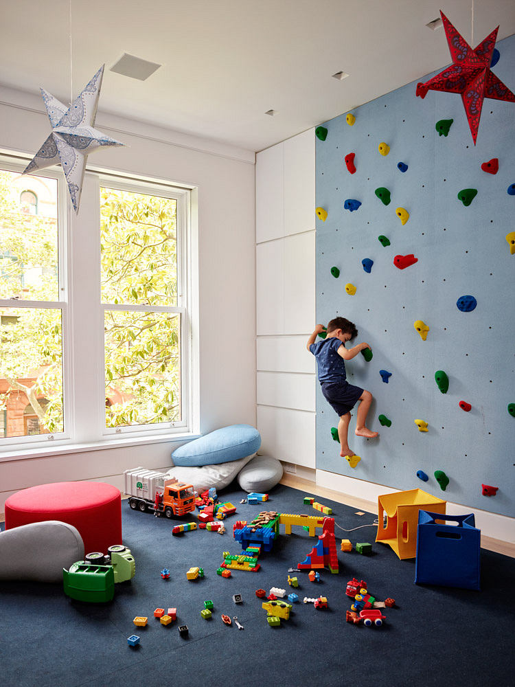 Child's playroom with a colorful climbing wall and scattered toys.