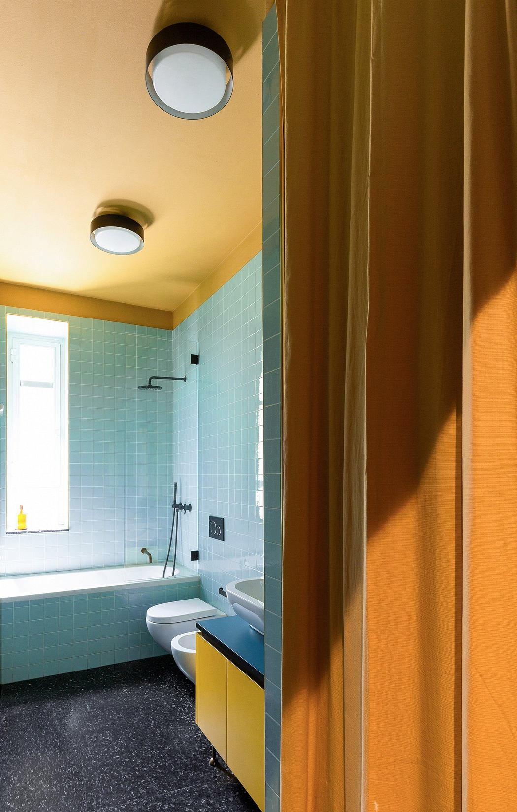 Colorful bathroom with blue tiles, yellow walls, and retro fixtures.