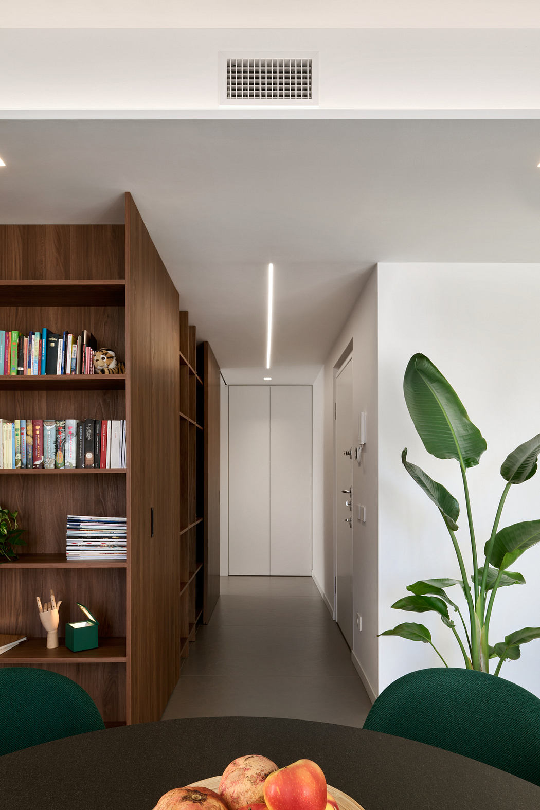 Modern hallway with wood bookshelf, LED strip lighting, and an indoor plant.