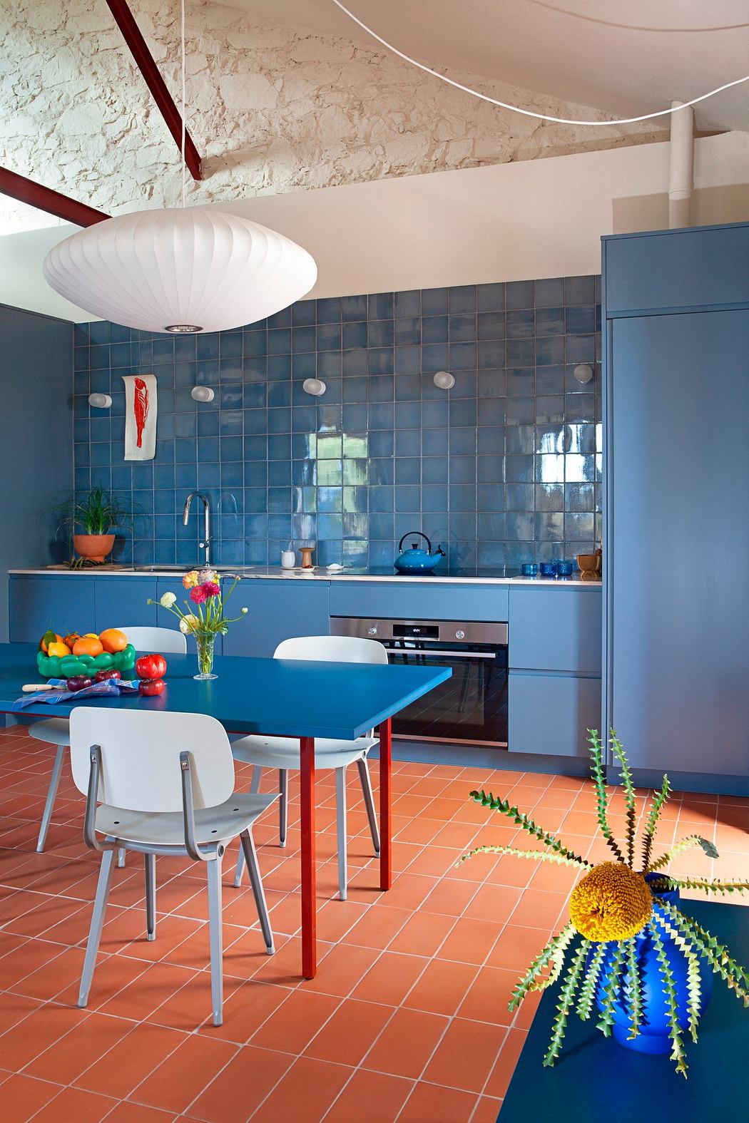 Vibrant kitchen interior with blue cabinets, terracotta tile floor, and