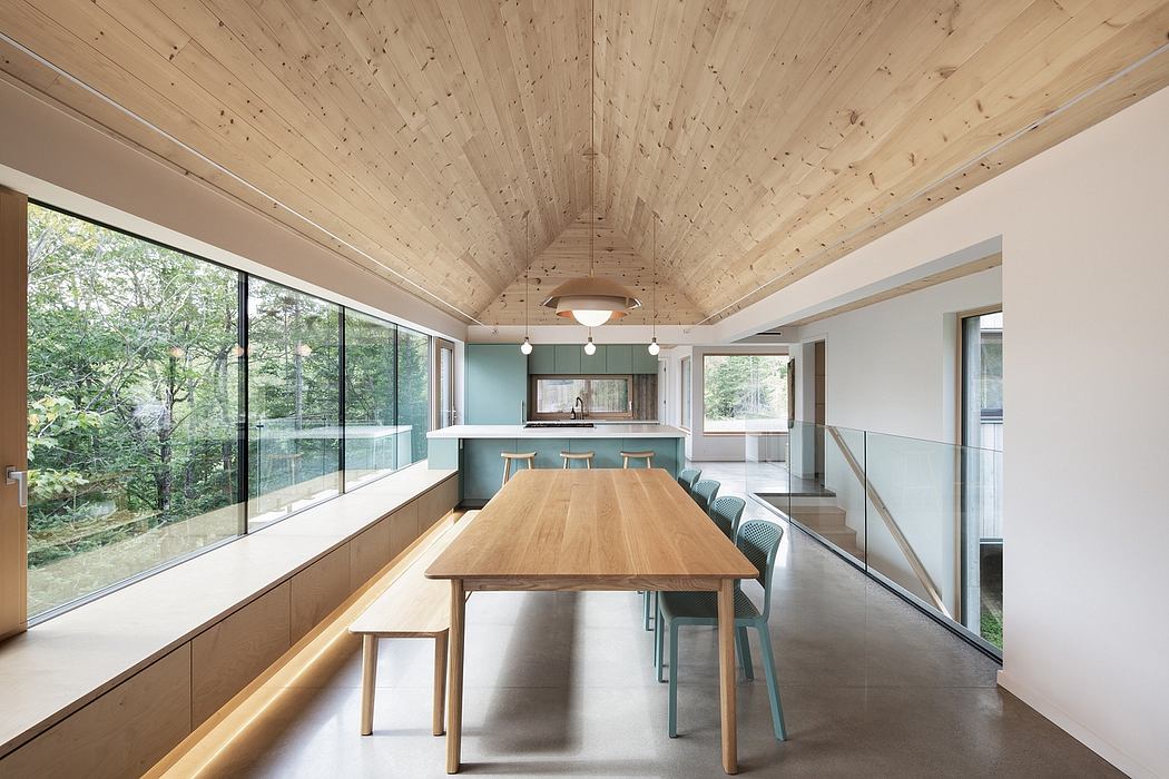 Minimalist dining area with wood ceiling, large windows, and sleek furniture.