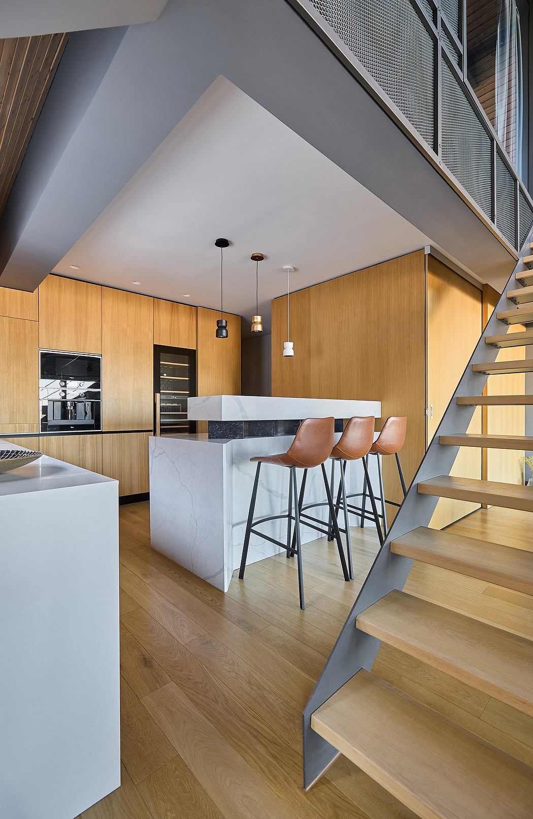 Sleek interior with wooden finishes, minimalist staircase, and high ceiling.