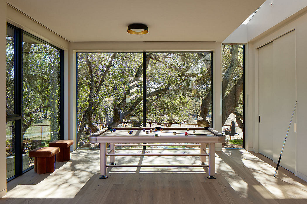 Contemporary room with pool table, large windows, and a woodland view.