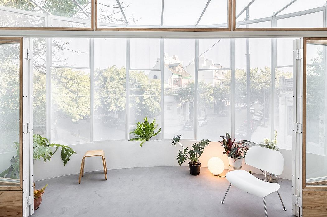 Bright sunroom with transparent walls, minimalist furniture, and potted plants.