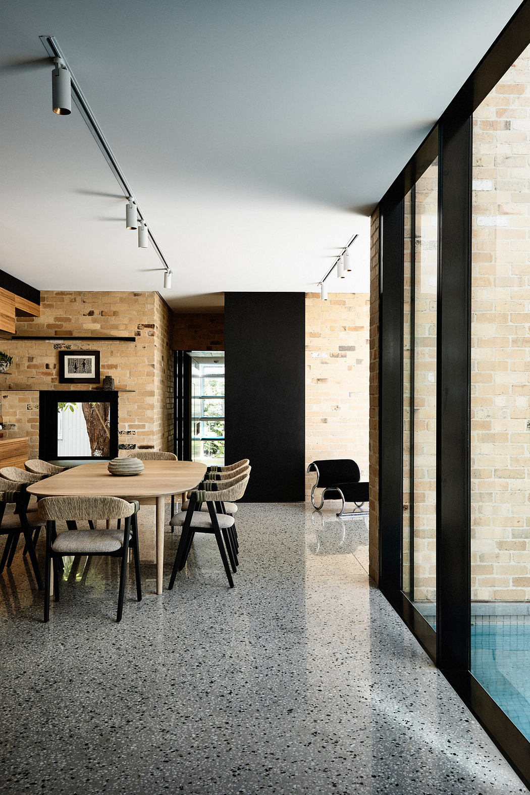 Modern dining room with exposed brick walls and floor-to-ceiling windows next to a