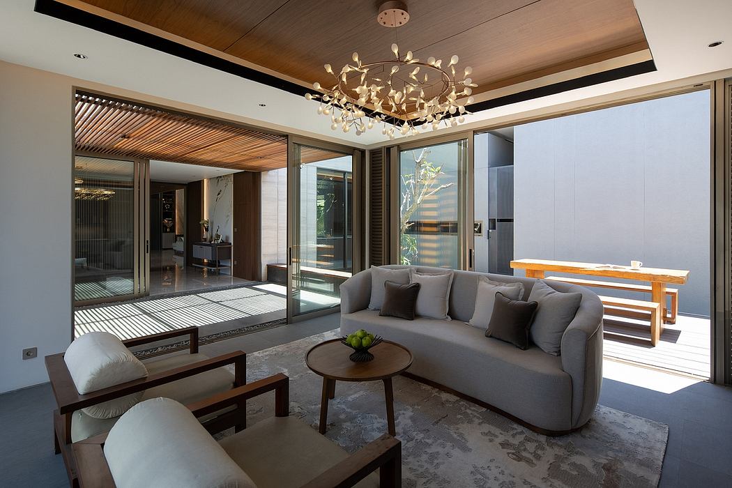 Modern living room with sofa, chairs, and chandelier, opening onto a patio