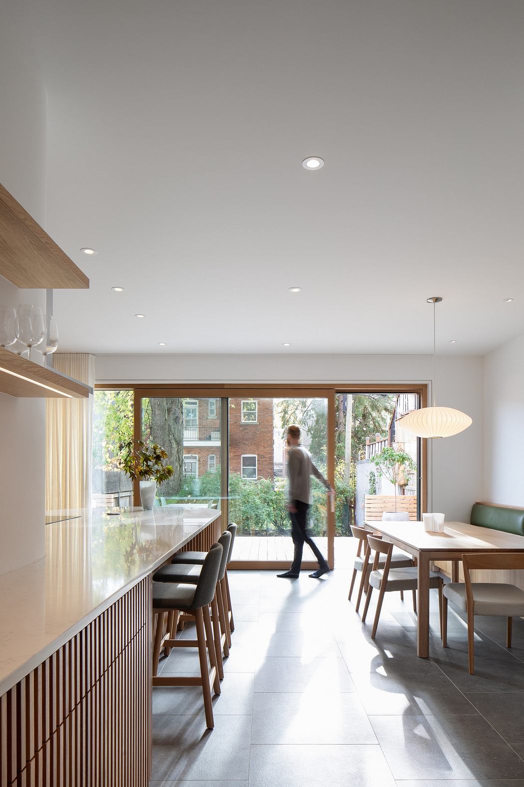 Modern kitchen with dining area leading to a garden, person in the background.