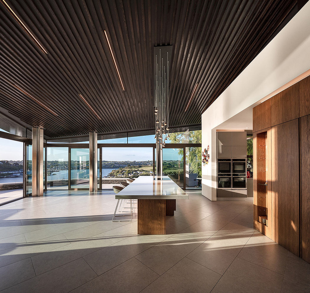 Modern kitchen with wooden accents and large windows overlooking a body of water.