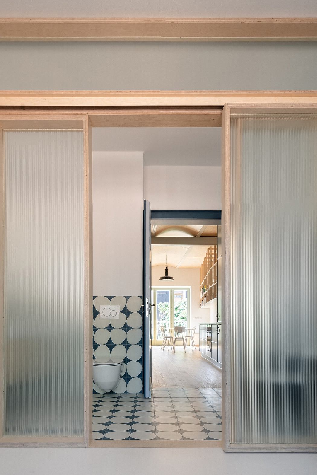 A view through an open door revealing a bathroom on the left and an adjoining room