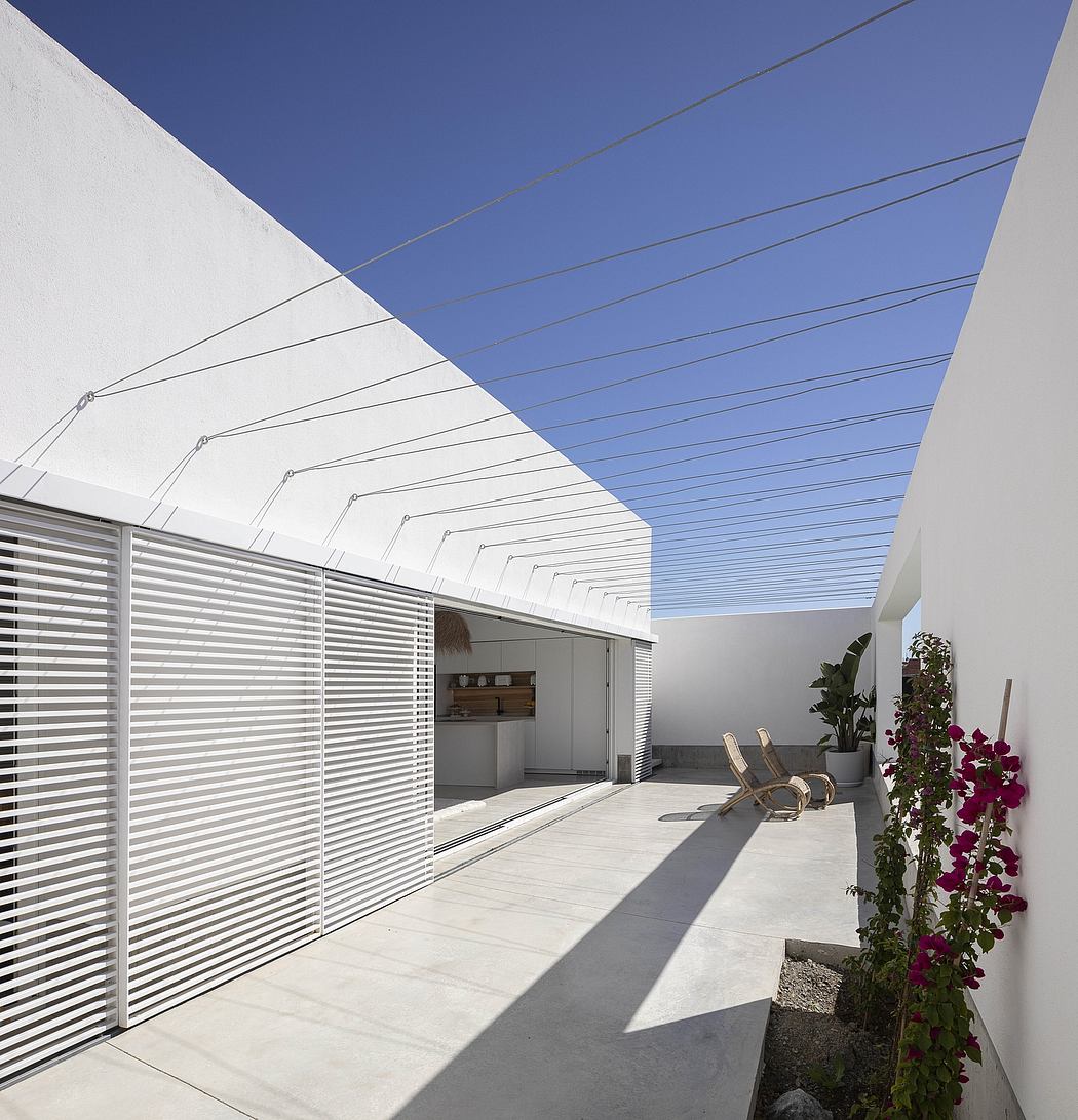 Modern courtyard with white walls, linear design, and a lounge chair.