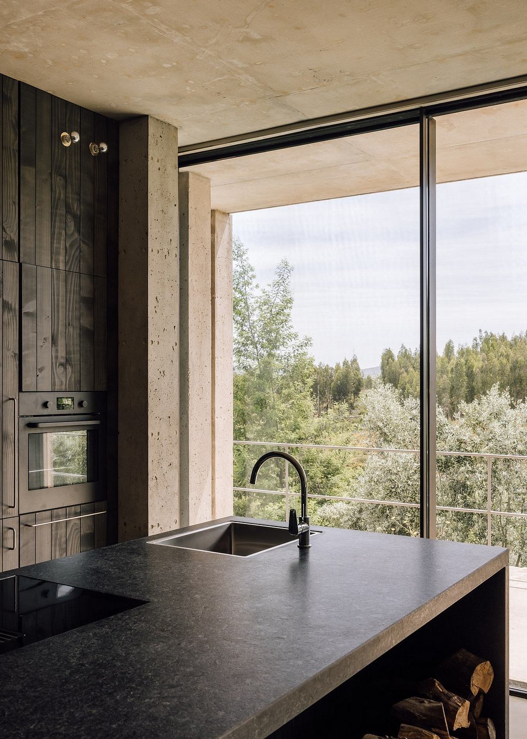 Modern kitchen with large window overlooking woods.
