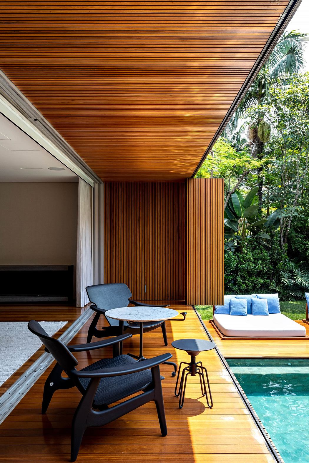Contemporary patio with wooden ceiling, designer chairs, and poolside view.